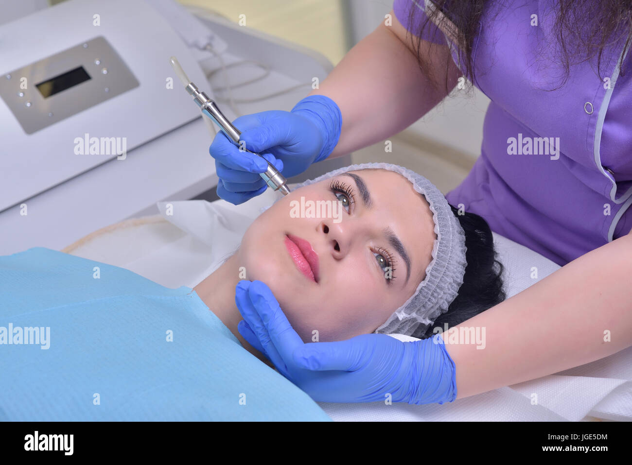 Young beautiful woman gets professional facial skin treatment in a professional beauty clinic. Stock Photo