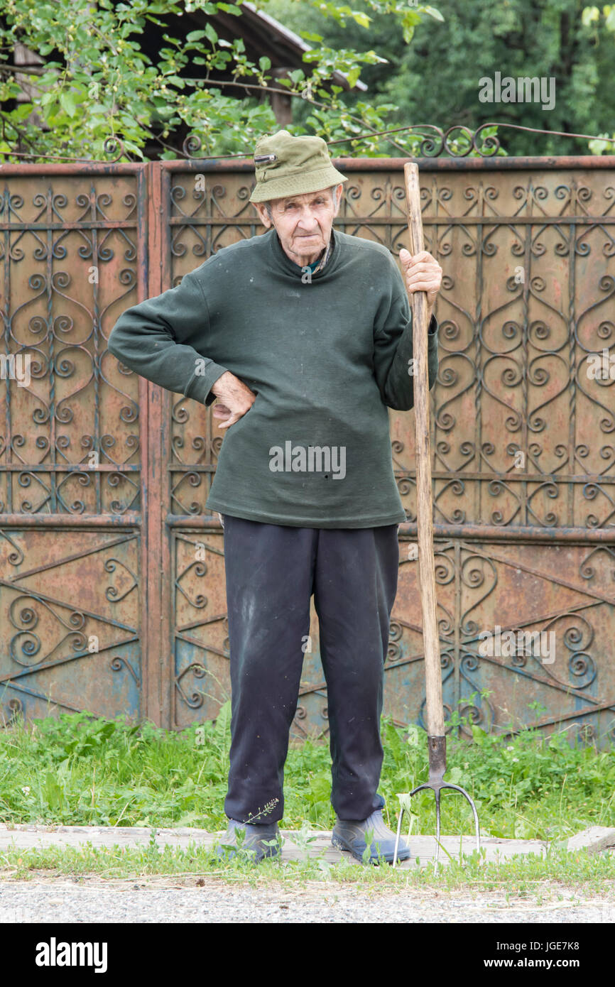 A man with the pitchfork lay on the road to a small village in the Maramures region, Romania Stock Photo