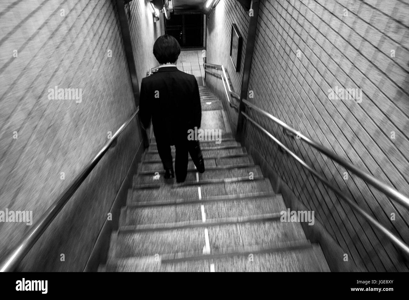 Japanese businessman in a suit walking down staircase at Higashi-Ginza station, Tokyo, Japan Stock Photo