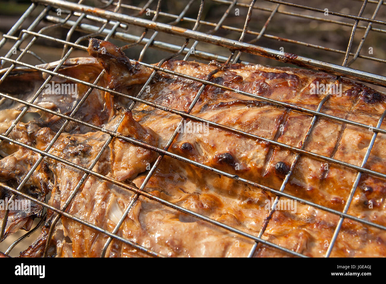 Close up view of fresh fish with sauce cooked on an open flame grill