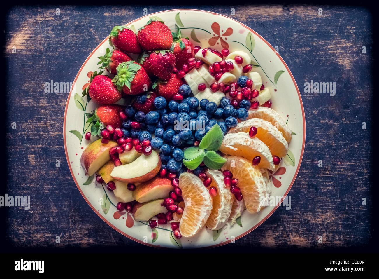 A closeup view of a platter of mixed fruits including strawberries, oranges, blueberries, apples and bananas Stock Photo