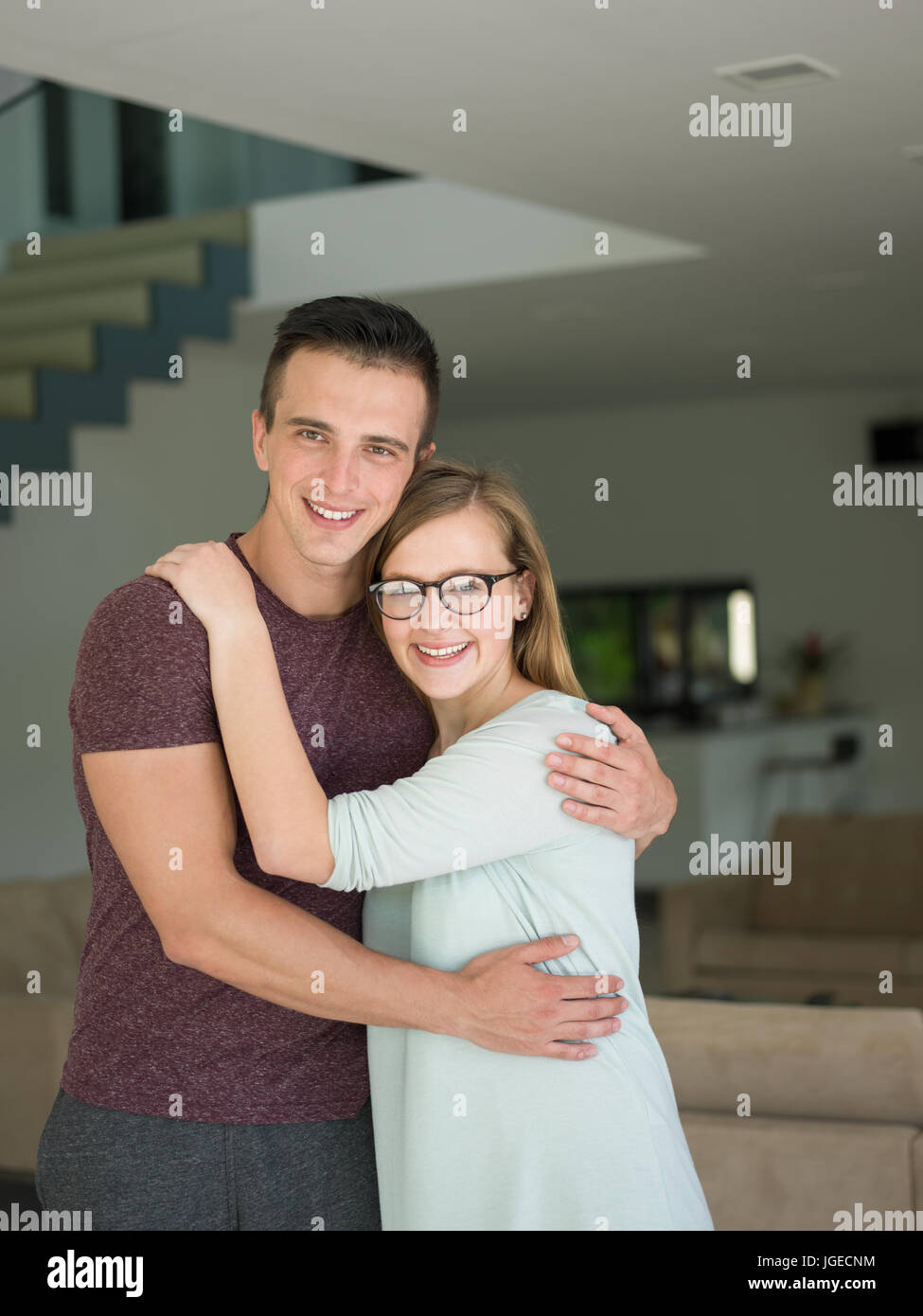 Portrait of a happy young beautiful couple hugging in their new home ...