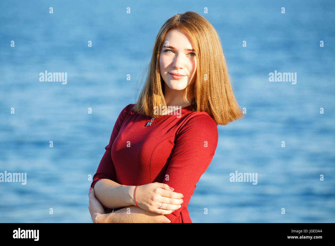 Young beautiful woman in red dress standing at seashore Stock Photo - Alamy
