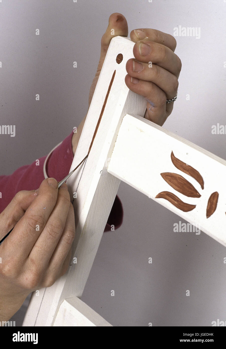 Close-up of hands stenciling a wooden chairStep x steps Stock Photo