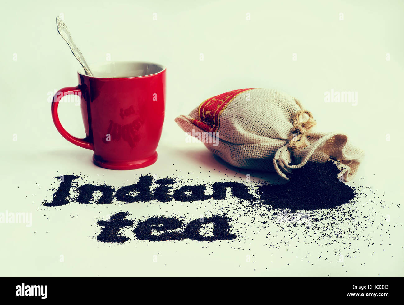 The word tea from of black tea powder with petals on white background