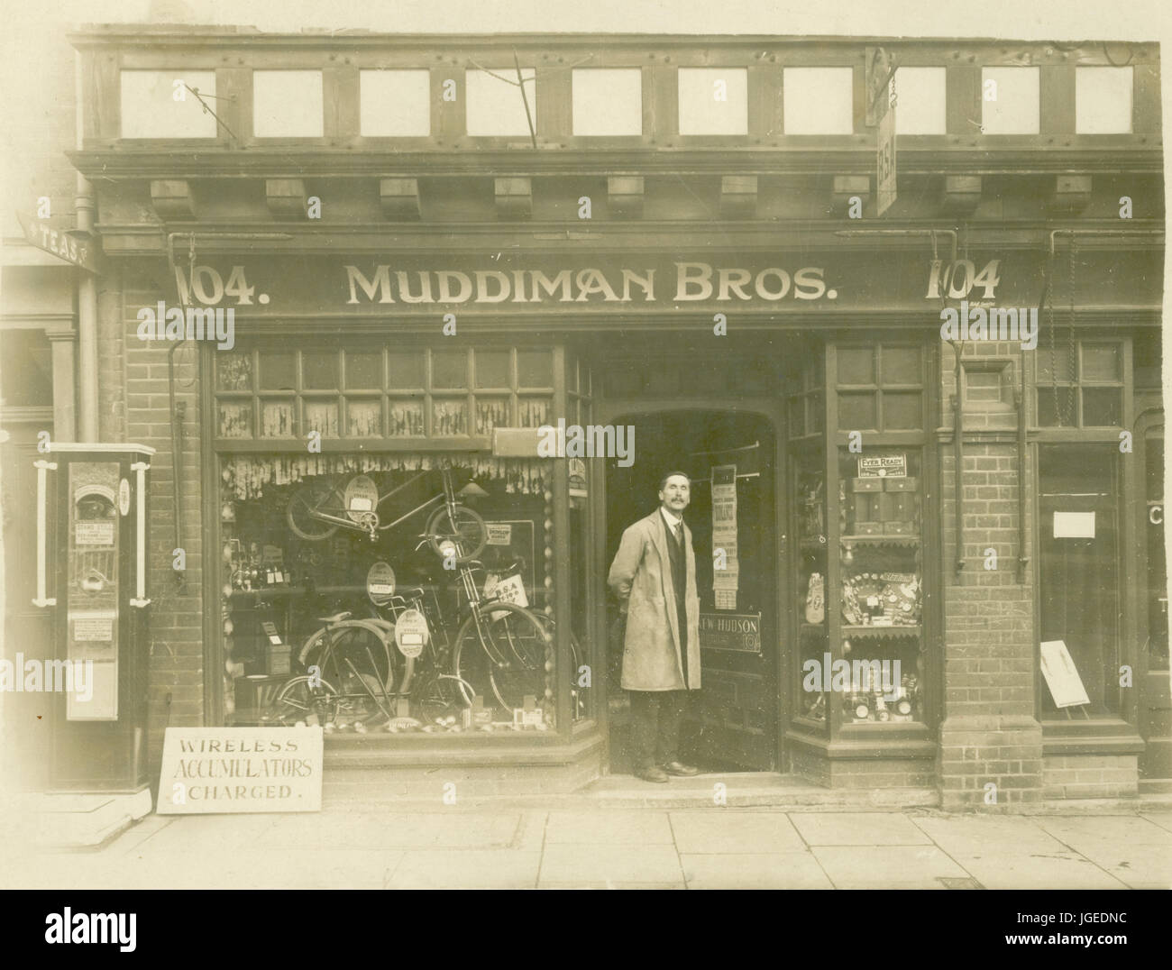 Postcard of man, possibly the proprietor, staff / assistant / assistants outside Muddiman Bros. cycle shop, 1930, 104 High St. possibly Suffolk, England, U.K. Stock Photo