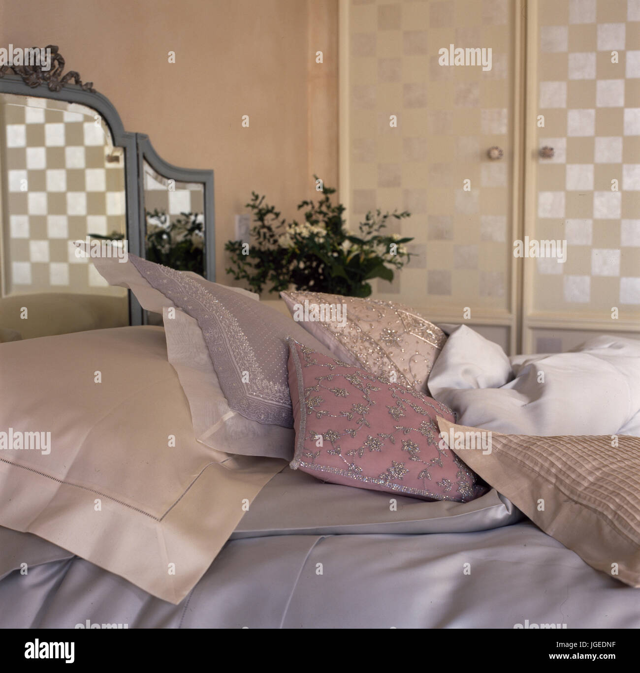 Bed with mirrored headboard and pastel cushions and pillows Stock Photo