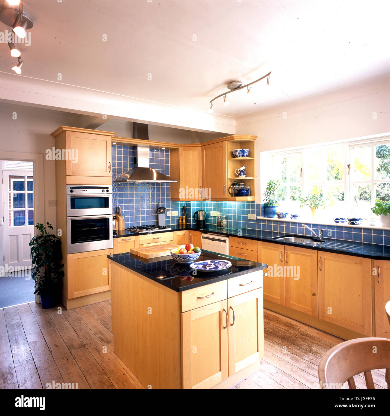 Island unit in kitchen with blue tiles and wooden fitted units Stock Photo