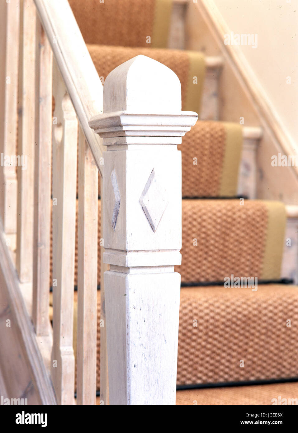 Stripped and painted newel post and banisters on stairs with sisal carpet Stock Photo