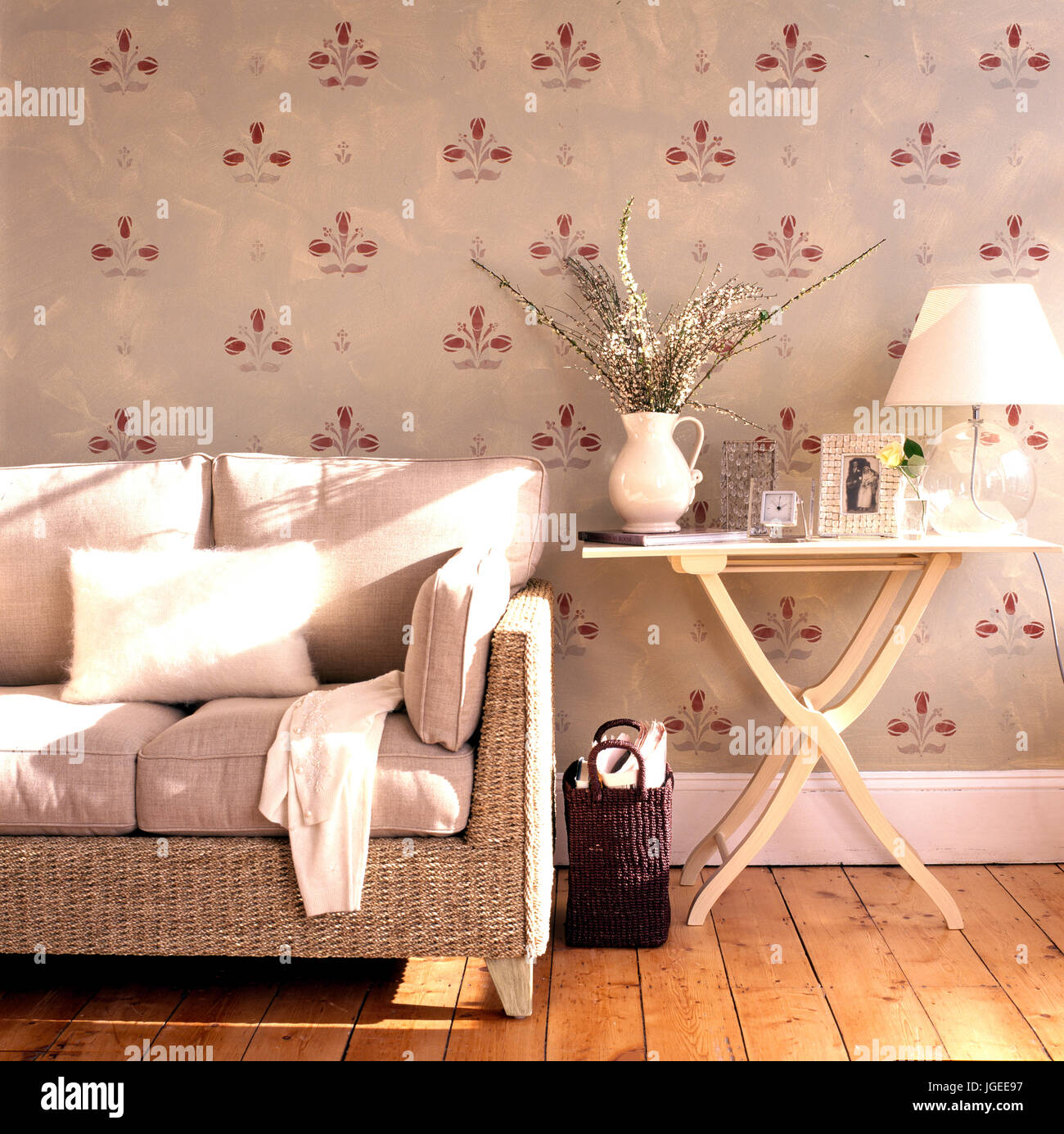 Stenciled wall and rattan sofa in living room with neutral colour scheme Stock Photo