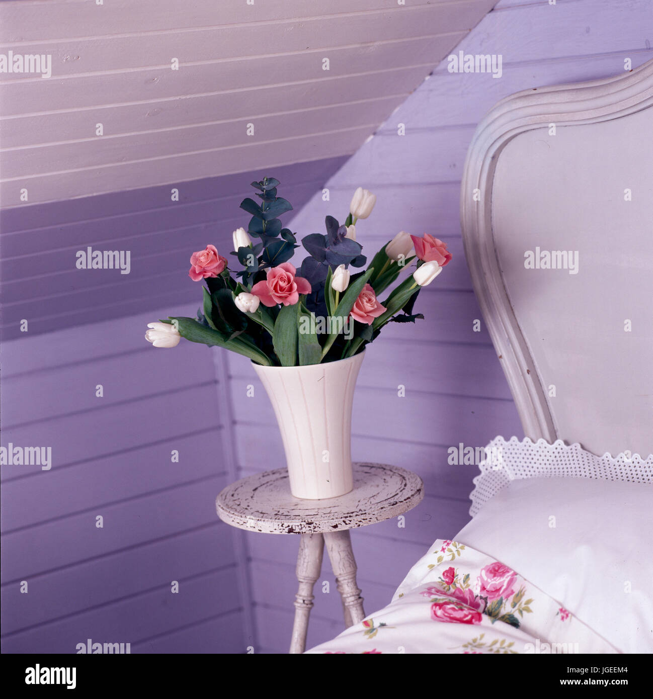 Closeup of flowers in corner of mauve bedroom ith tongue+groove panelled walls Stock Photo