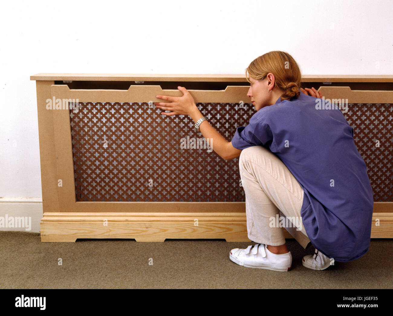 Woman fitting a radiator cover. Step x step craft & DIY projects Stock Photo