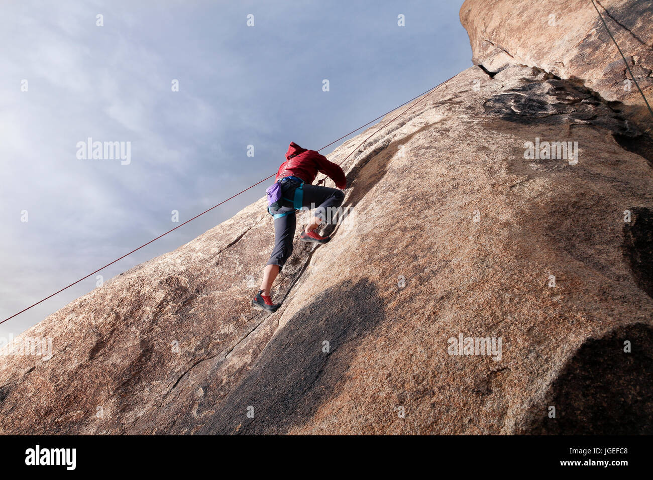 Young caucasian woman rock climbs in the desert Stock Photo