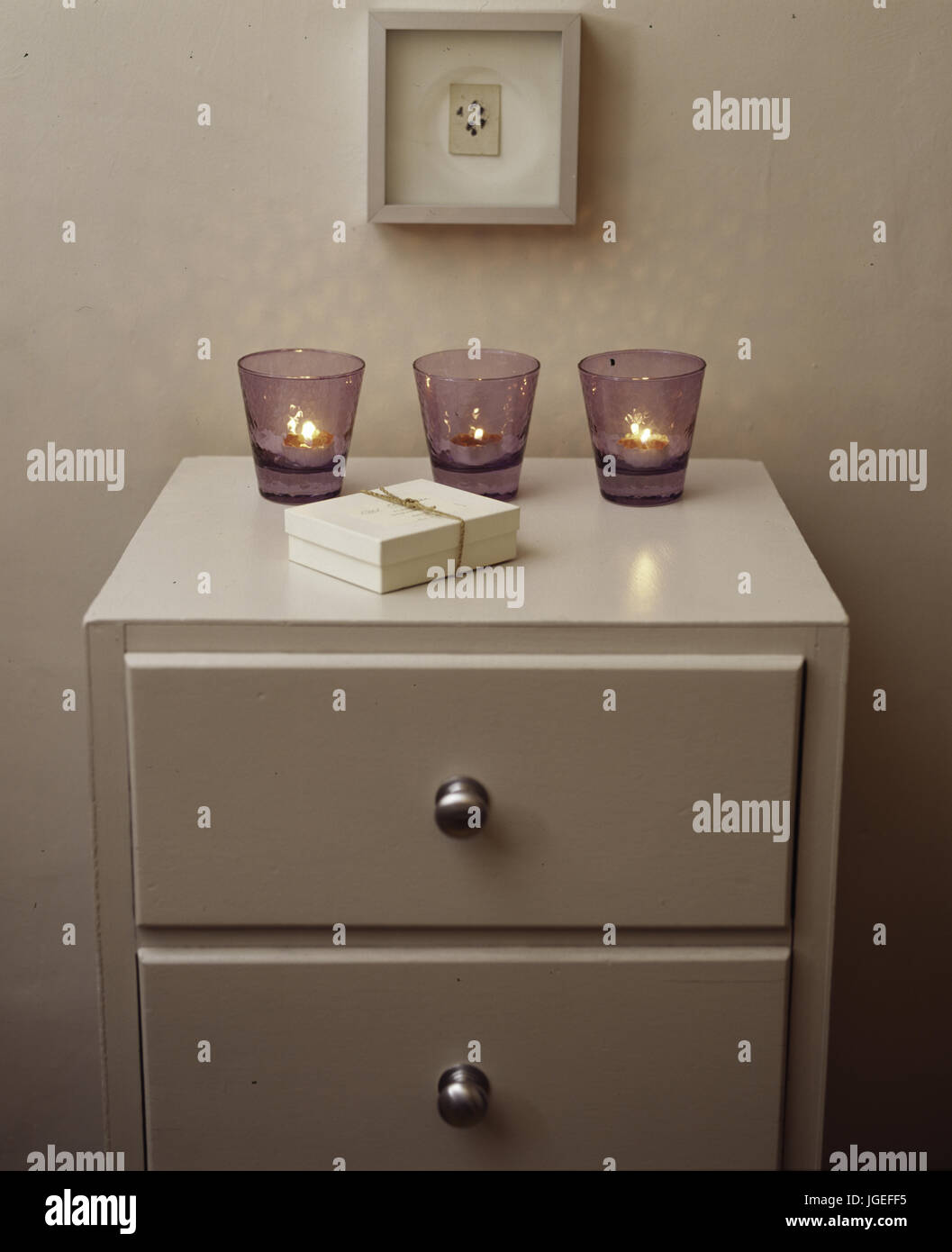 Small chest of drawers with three nightlights in glasses Stock Photo
