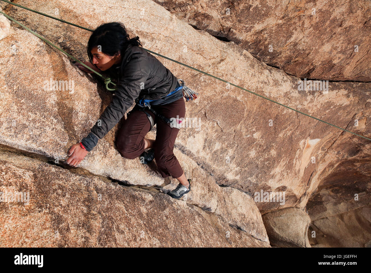 Young south asian woman rock climbs in the desert on a very difficult ...