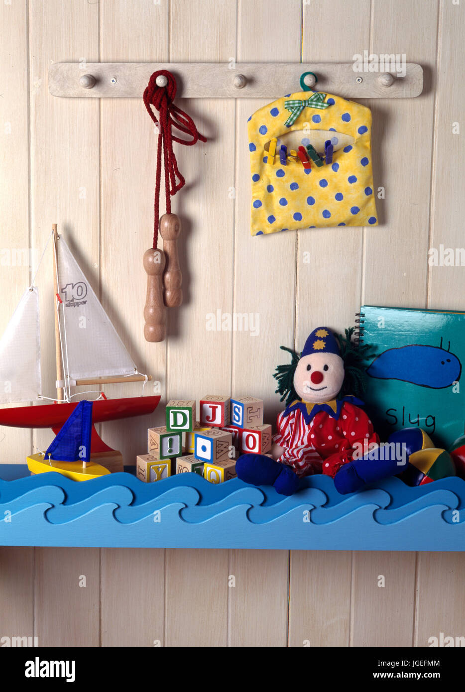 Toys on child's nautical themed shelf on tongue+roove wall Stock Photo