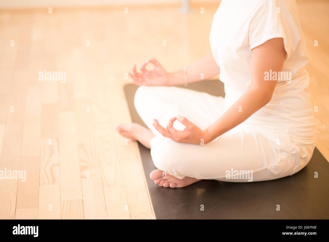 Young beautiful woman meditating in lotus pose sitting on the floor in ...