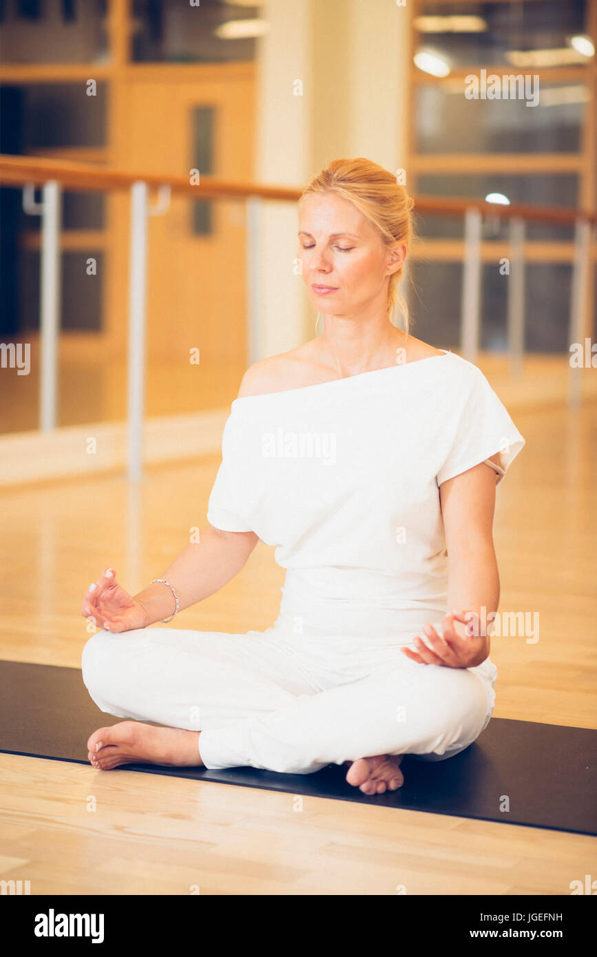 Young beautiful woman meditating in lotus pose sitting on the floor in ...