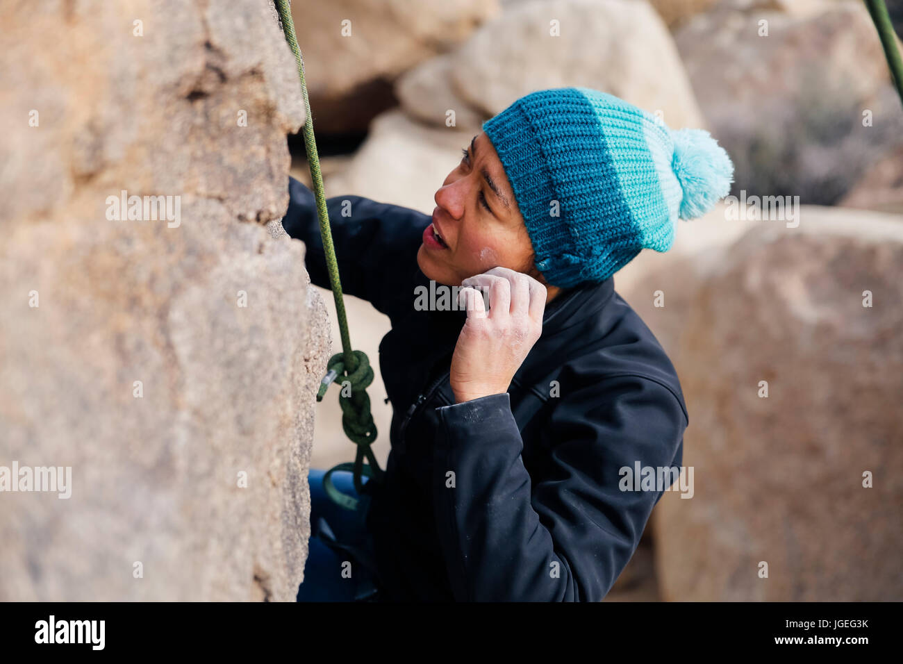 Young mixed race woman dressed for cold weather rock climbs in the desert Stock Photo