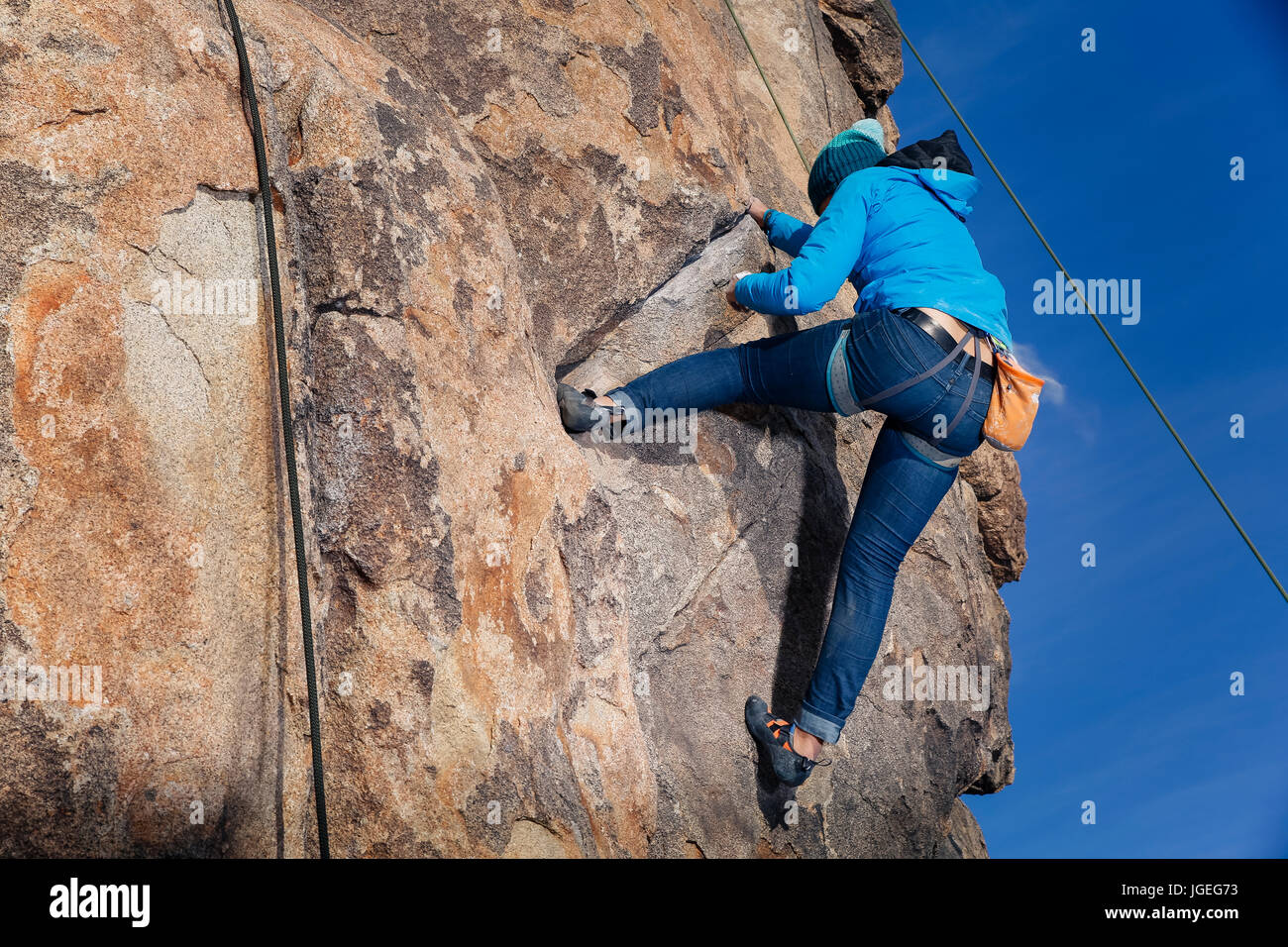 Young mixed race woman dressed for cold weather rock climbs in the desert Stock Photo