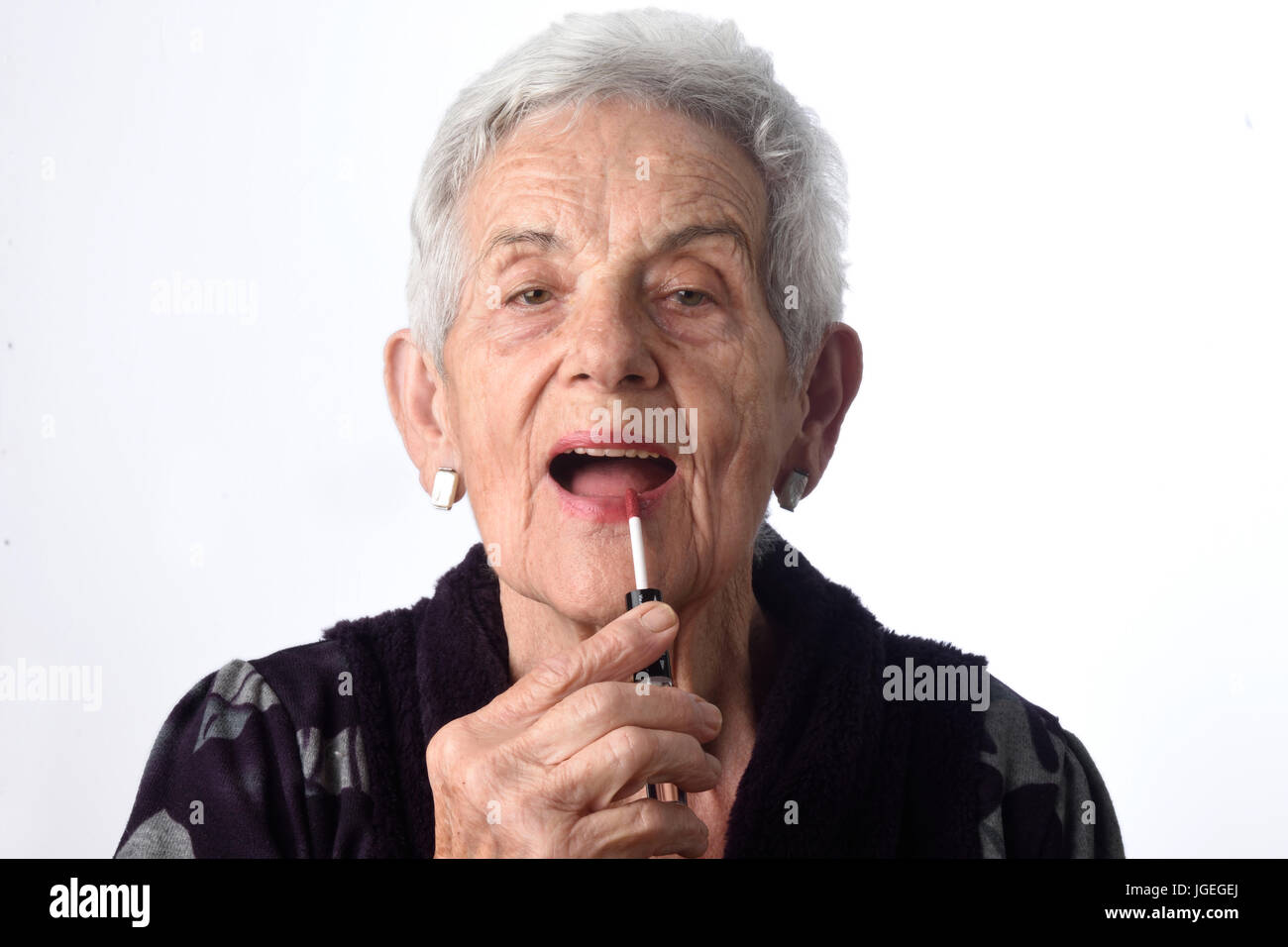 Old woman painting her lips on white background Stock Photo