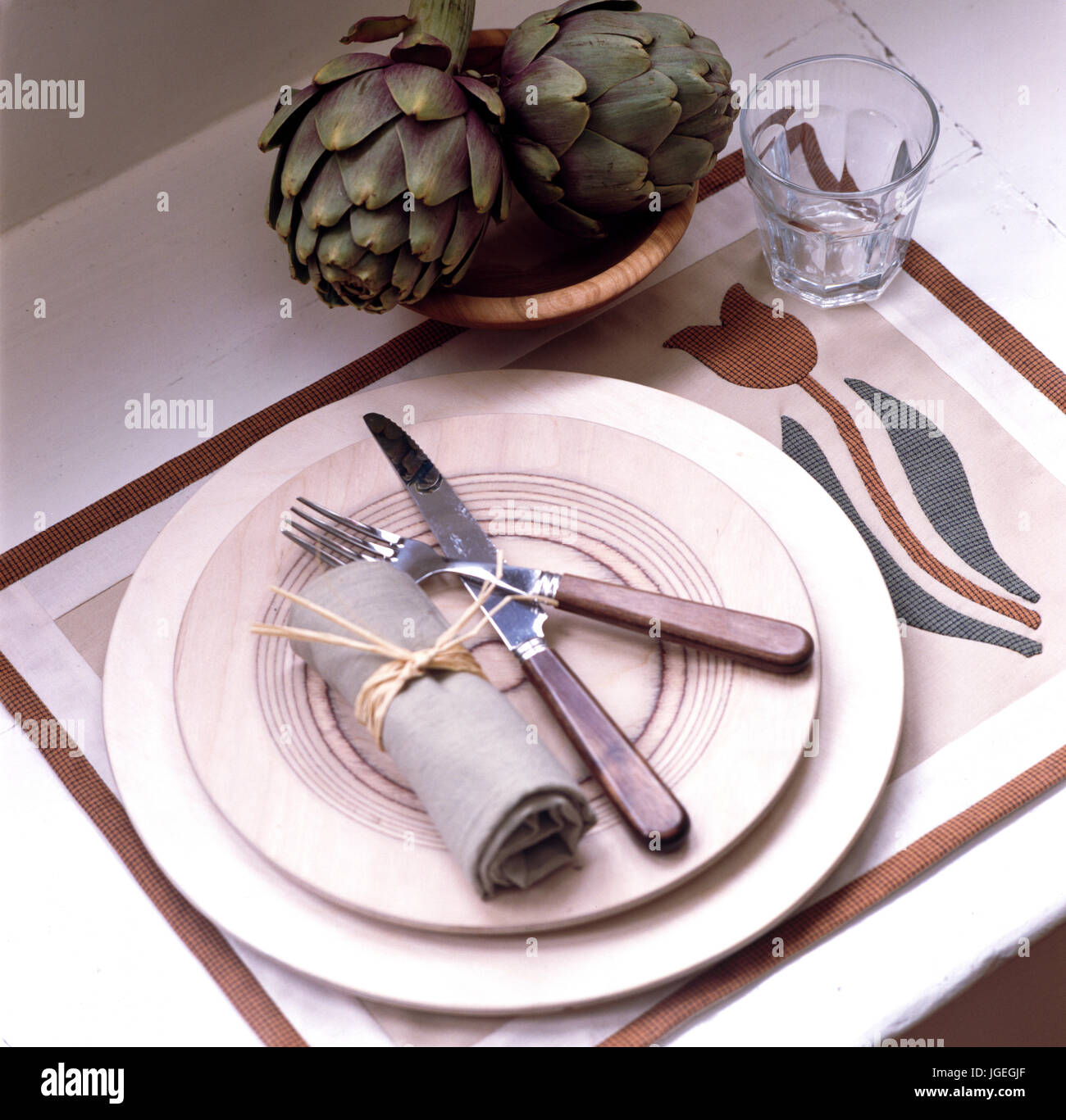 Knife and fork with linen napkin and plates on linen place mat Stock Photo