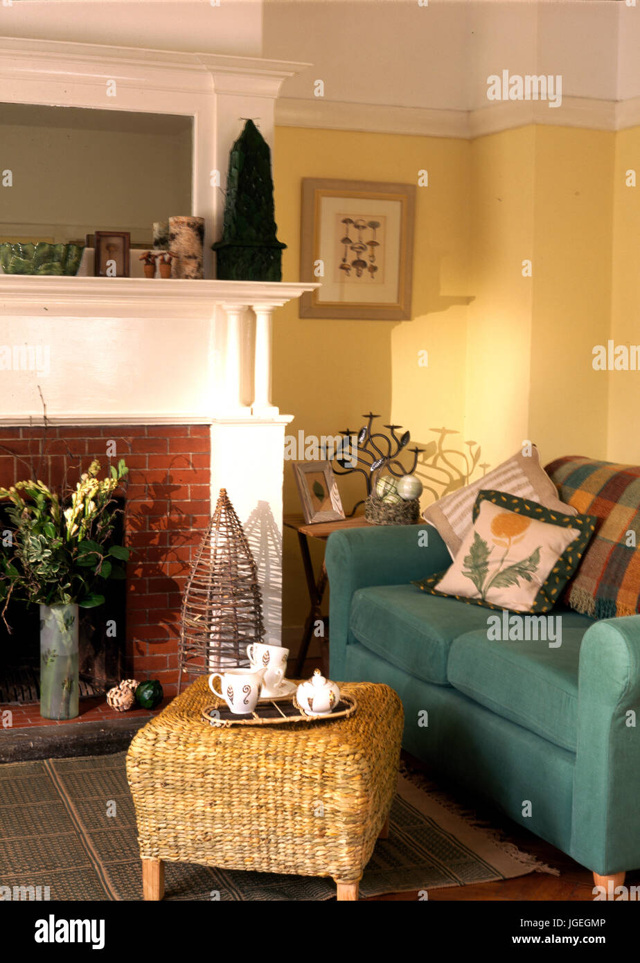 Corner of traditional living room with picture rail and wicker stool beside green sofa Stock Photo