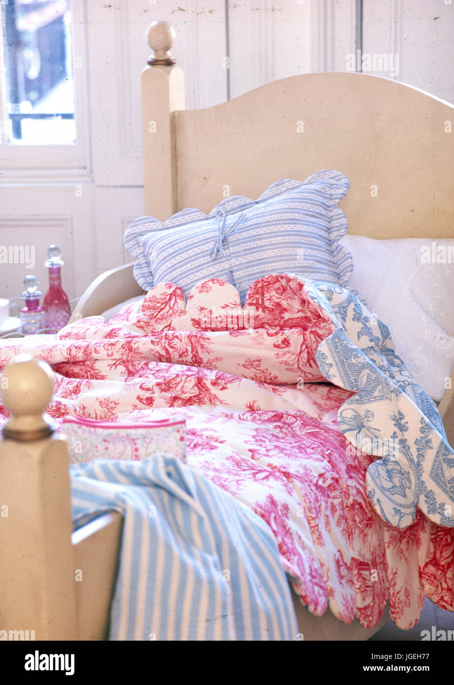 Single bed with Toile de Jouy quilt and striped pillows Stock Photo