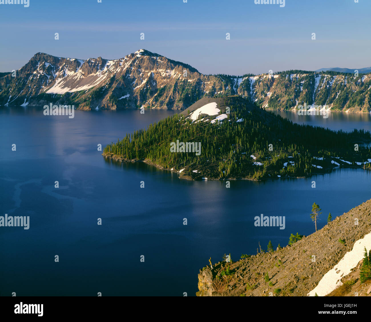 USA, Oregon, Crater Lake National Park, Sunrise on Crater Lake and Wizard Island with Garfield Peak  rising above Crater Lake; from Merriam Point. Stock Photo