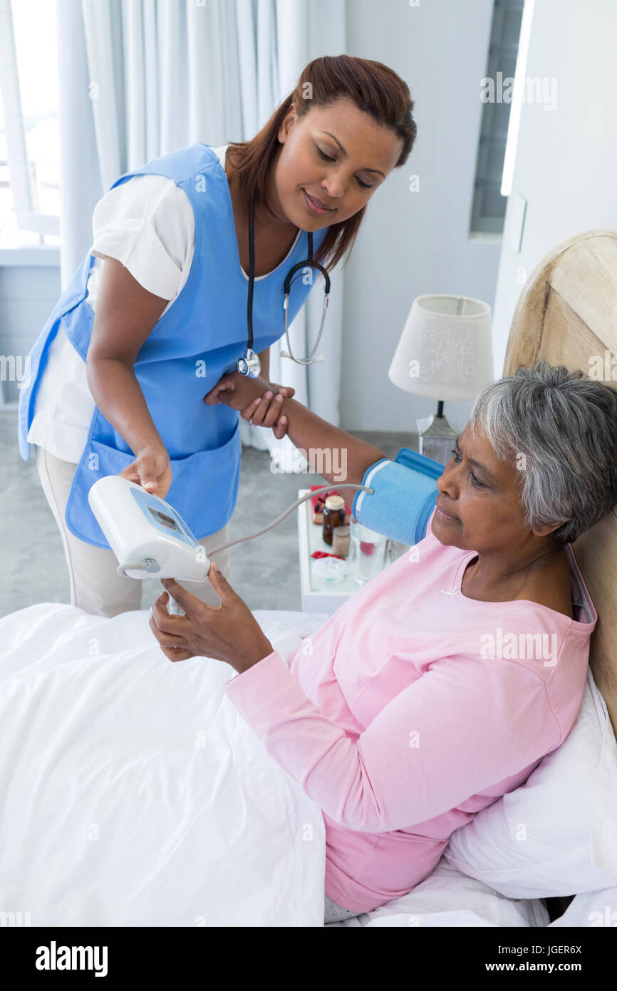 Female doctor measuring blood pressure of senior woman in bedroom Stock ...