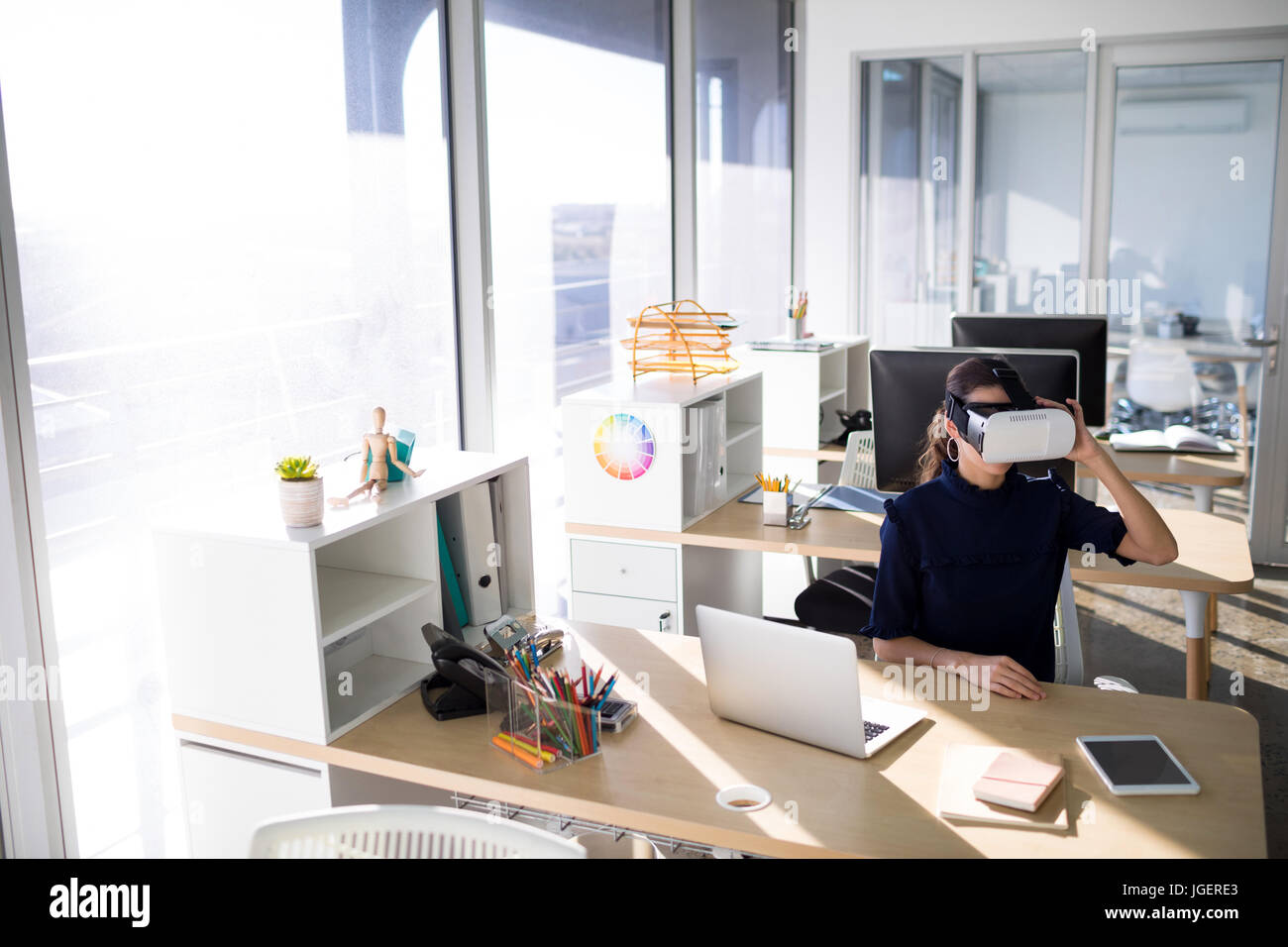Female executive using virtual reality headset at her desk in office ...