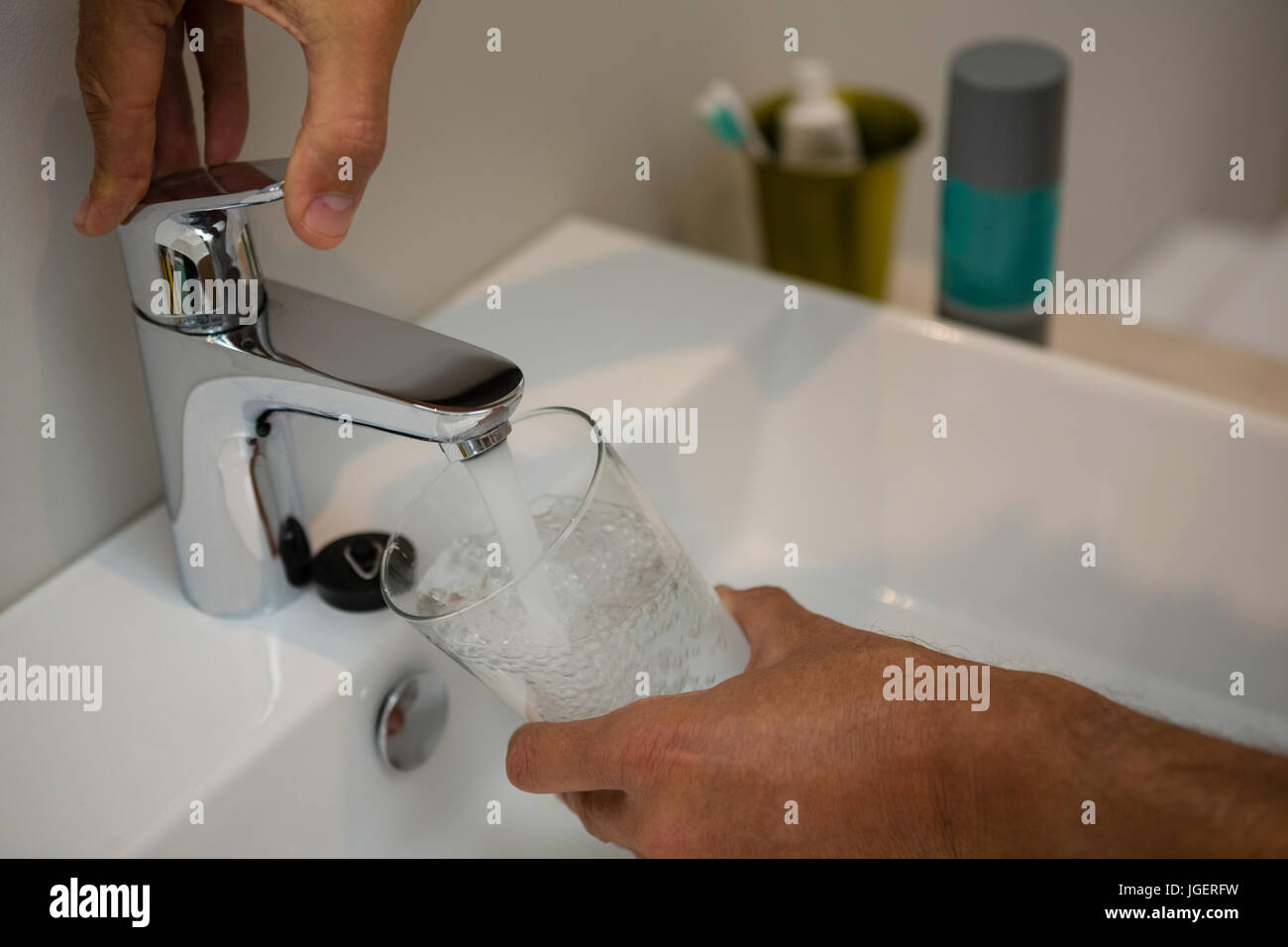 Man filling glass of water at sink in bathroom Stock Photo Alamy