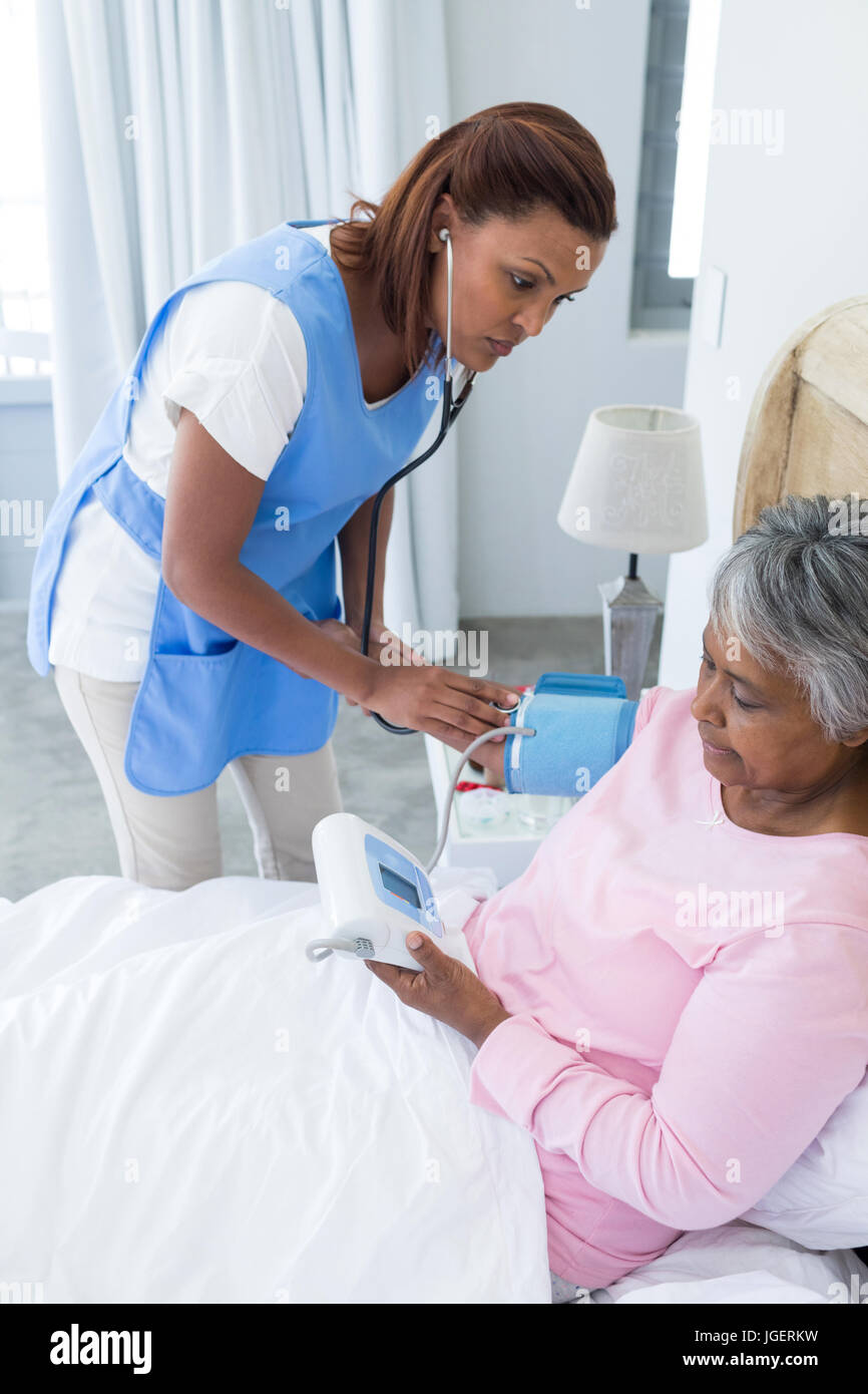 Female doctor measuring blood pressure of senior woman in bedroom Stock ...