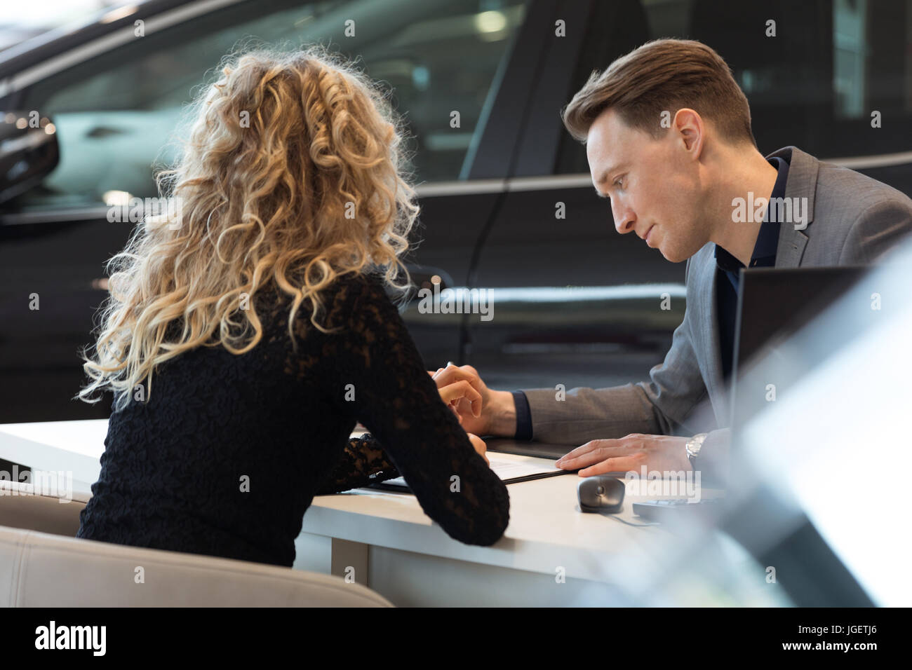 Car salesperson talking with customer in showroom Stock Photo