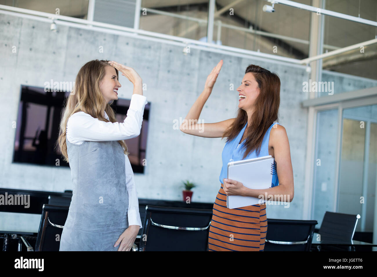 Female executives giving high five in office Stock Photo - Alamy