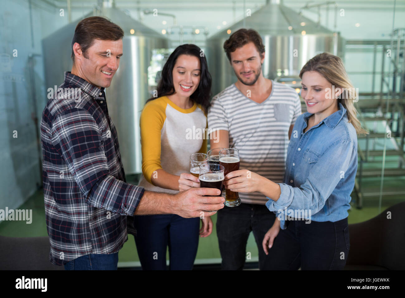 Happy friends toasting beer at factory Stock Photo - Alamy