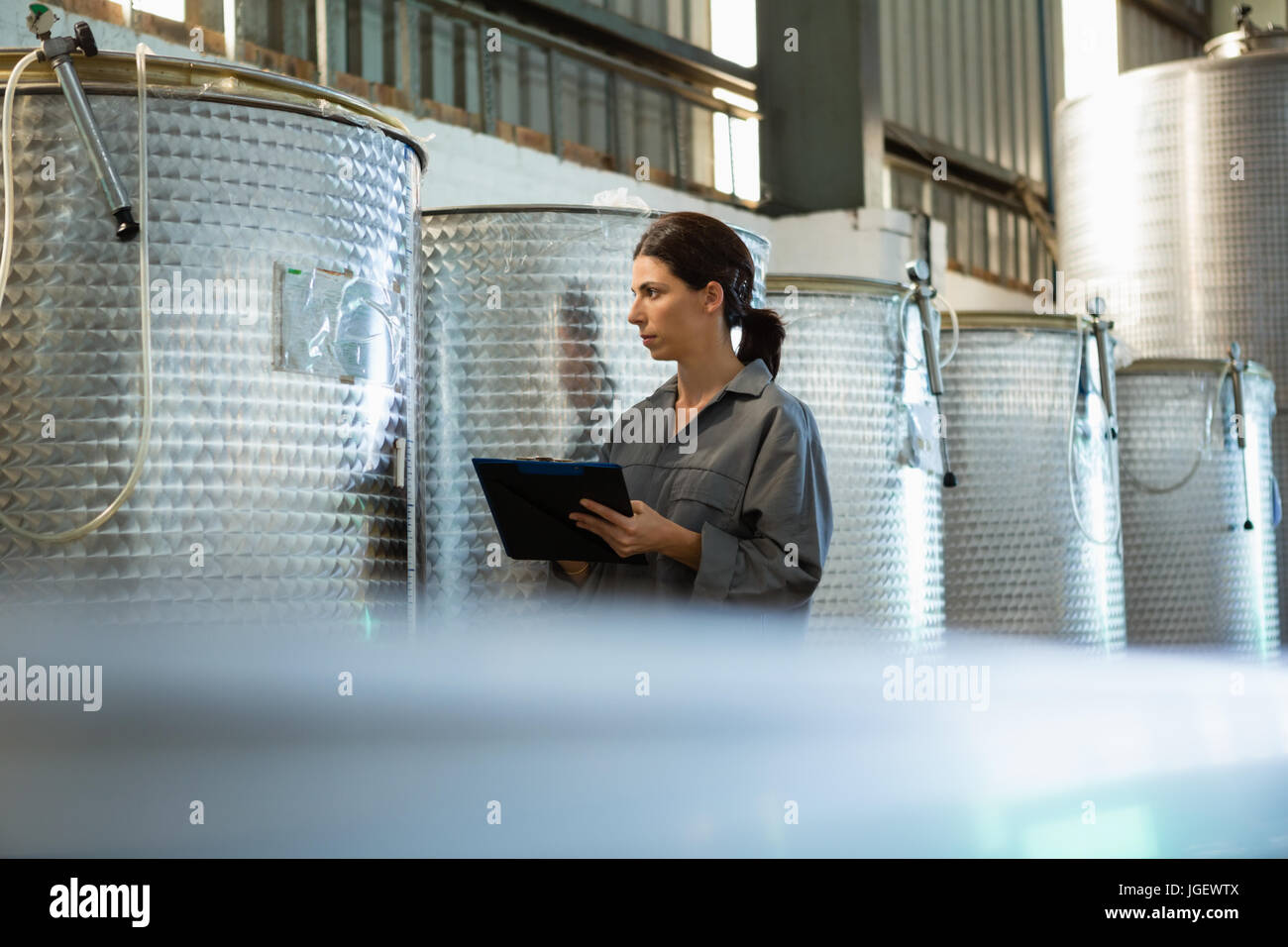 Attentive female worker writing on clipboard in olive factory Stock ...