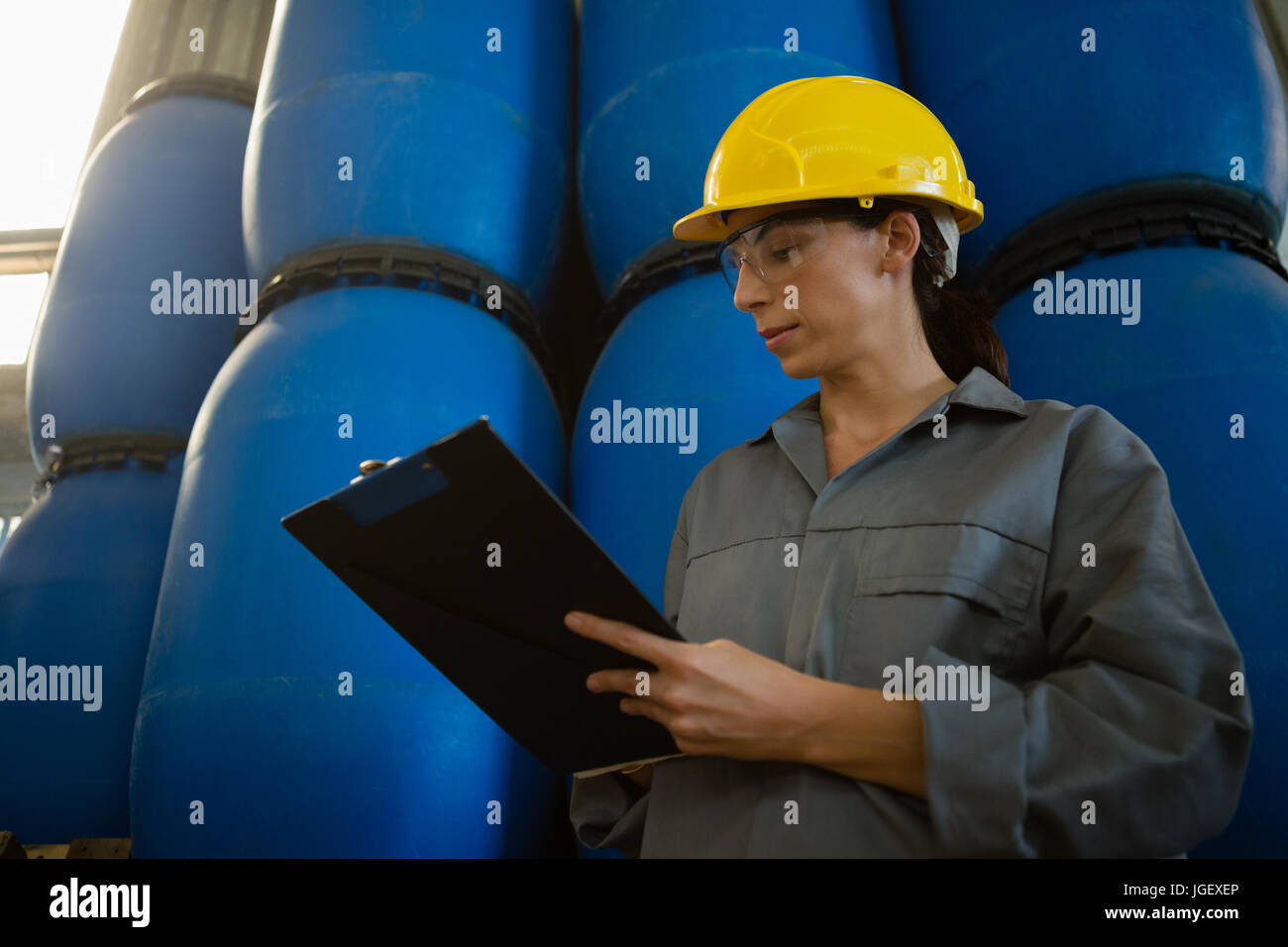 Attentive female worker writing on clipboard in olive factory Stock ...