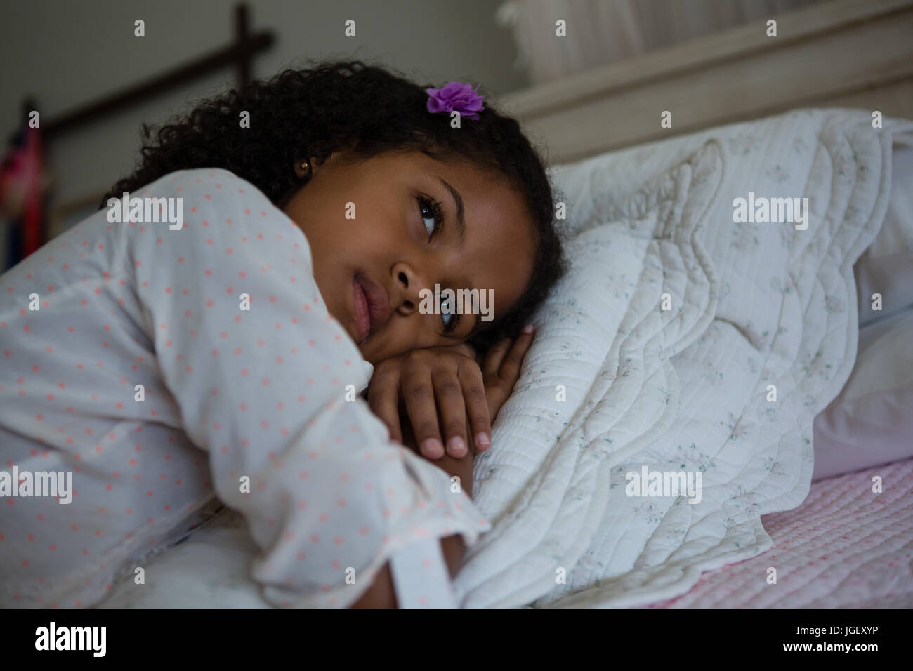 Thoughtful girl lying on a bed in the bedroom Stock Photo