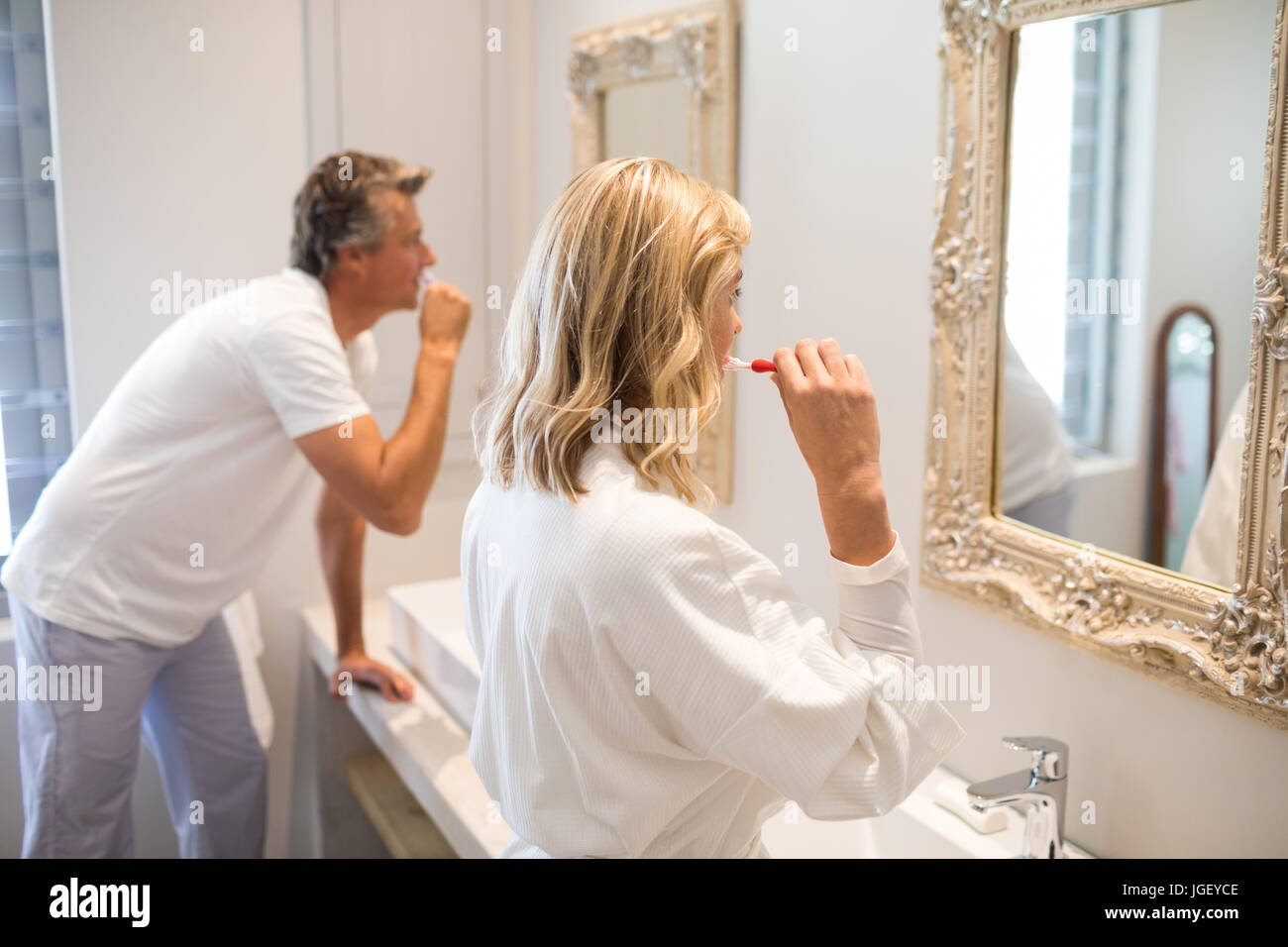 Couple brushing teeth in front of mirror at bathroom Stock Photo