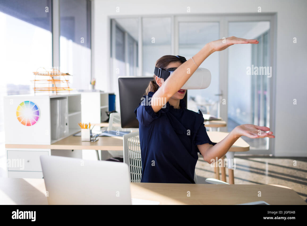 Female executive using virtual reality headset in office Stock Photo ...