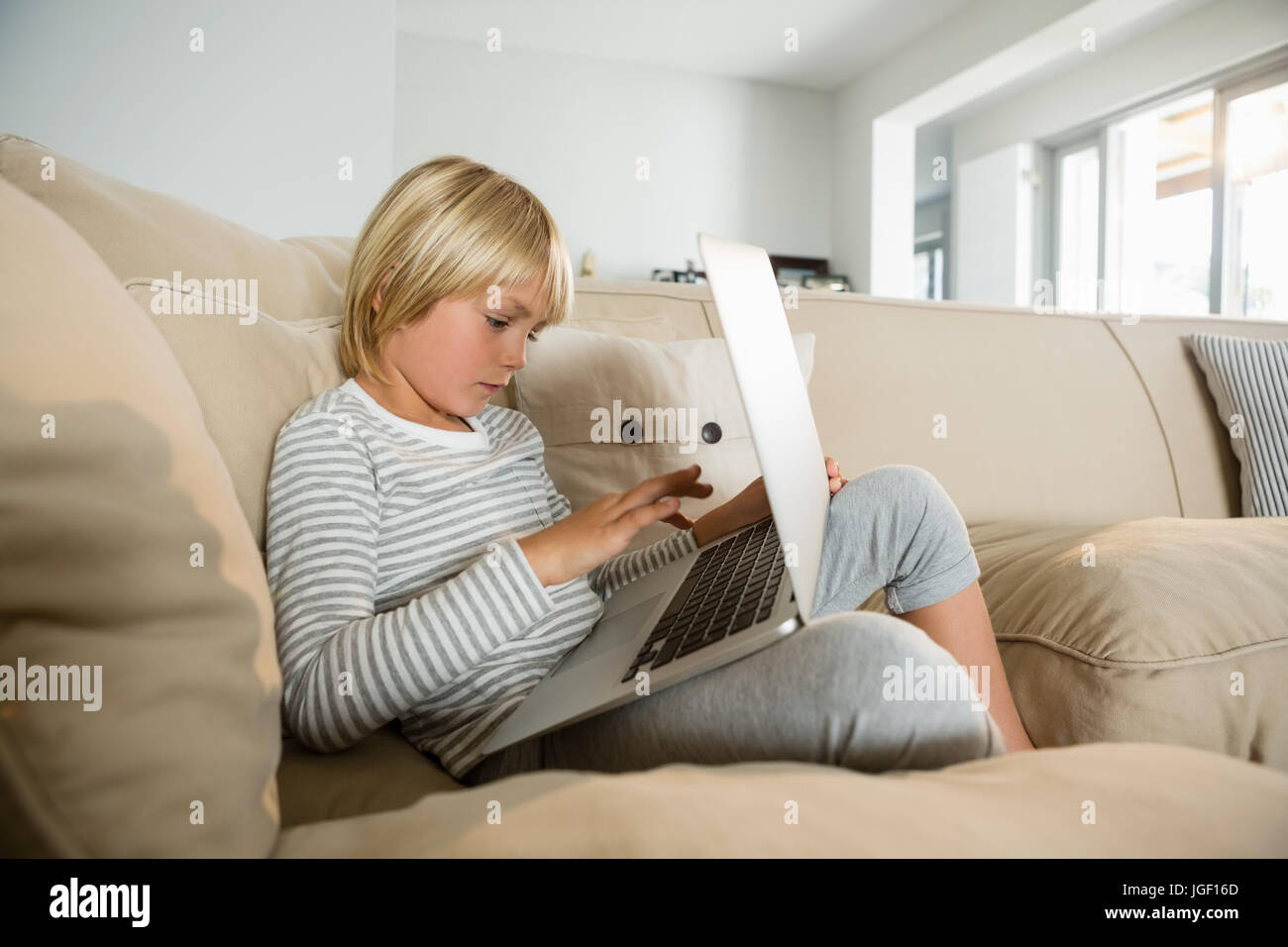 Boy using laptop in the living room at home Stock Photo - Alamy