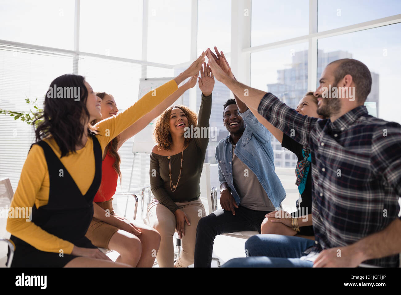 Group of happy executives giving high five to each other in office ...