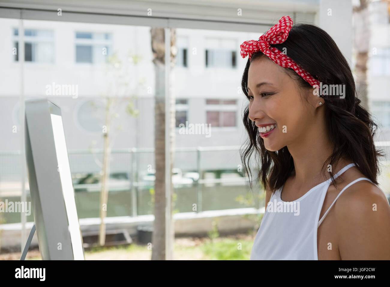 Smiling businesswoman using computer by window in office Stock Photo ...