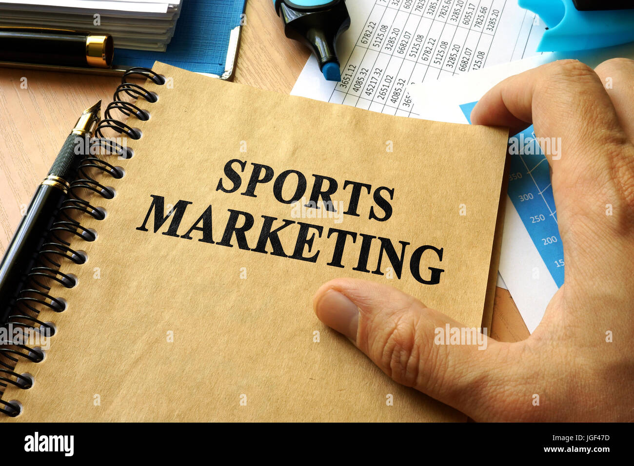 Hands holding book with title sports marketing. Stock Photo