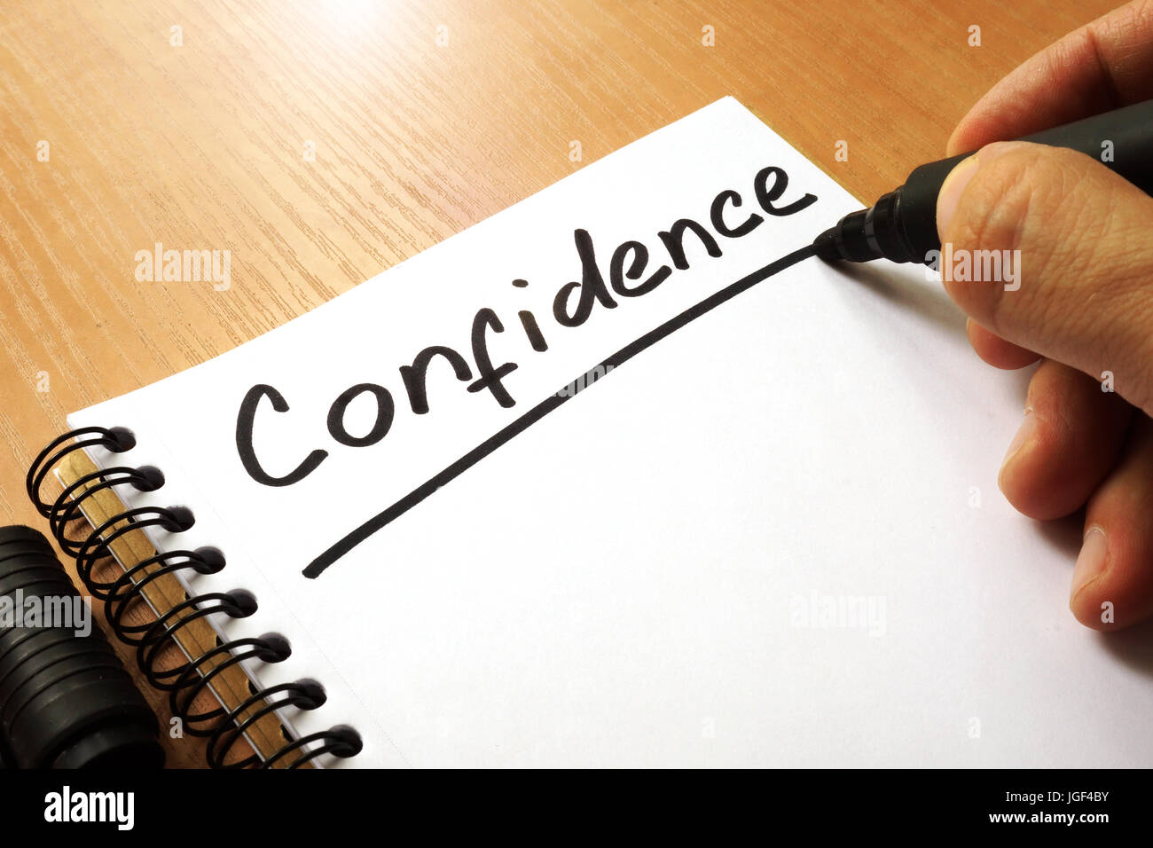 Hand is writing Confidence on a note. Stock Photo