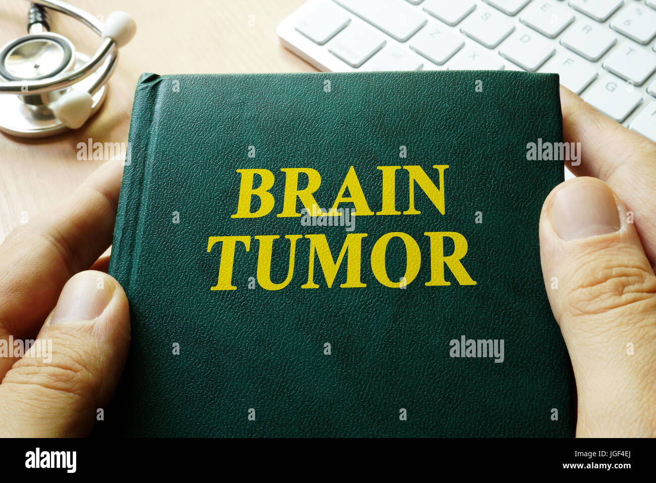 Book with title brain tumor in hands. Stock Photo