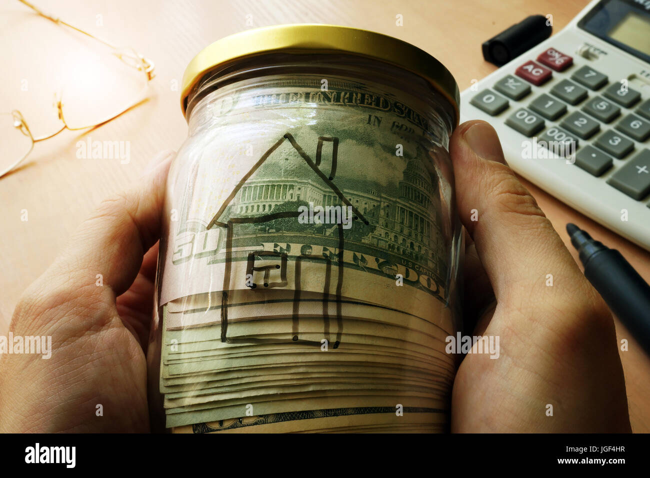 Jar with dollars and house on a side. Real estate rent and buy concept. Stock Photo