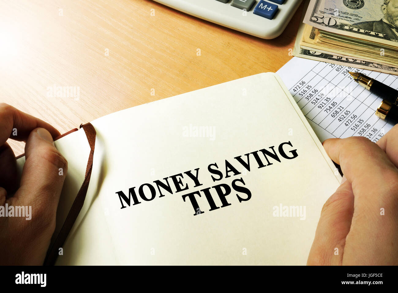Hands holding book with title money saving tips. Stock Photo