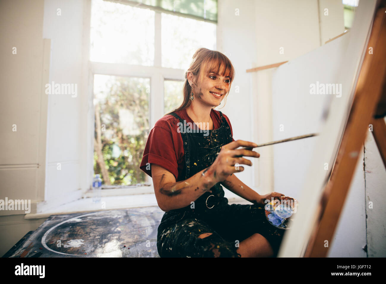 Indoor shot of female artist painting in studio. Woman painter painting in her workshop. Stock Photo